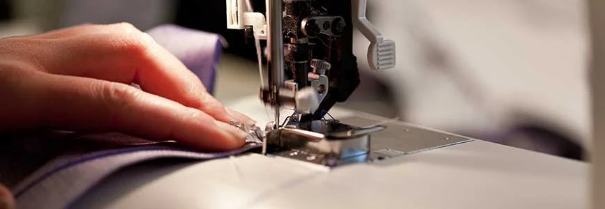 Person näht mit Nähmaschine Stoff